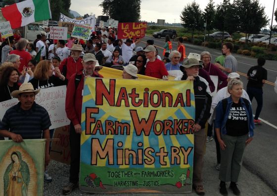 Farmworkers rally on the side of the road.