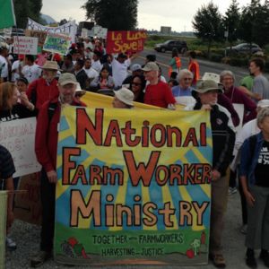 Farmworkers rally on the side of the road.