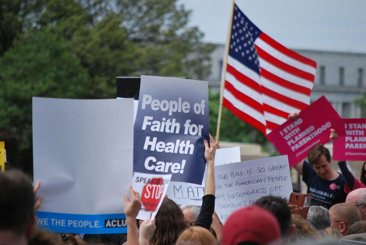 Rally sign reading "People of Faith for Health Care"