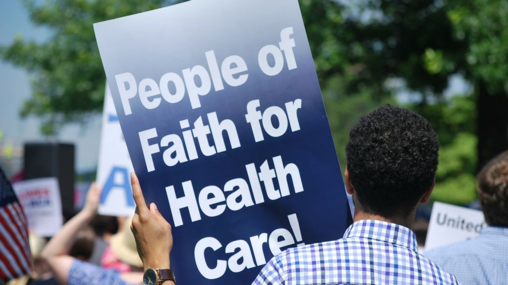 Person holding sign which reads, "people of faith for health care."