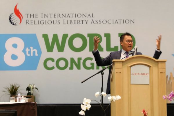 Bautista address the 8th world congress of the international religious liberty association. He stands behind a light-colored wooden podium.