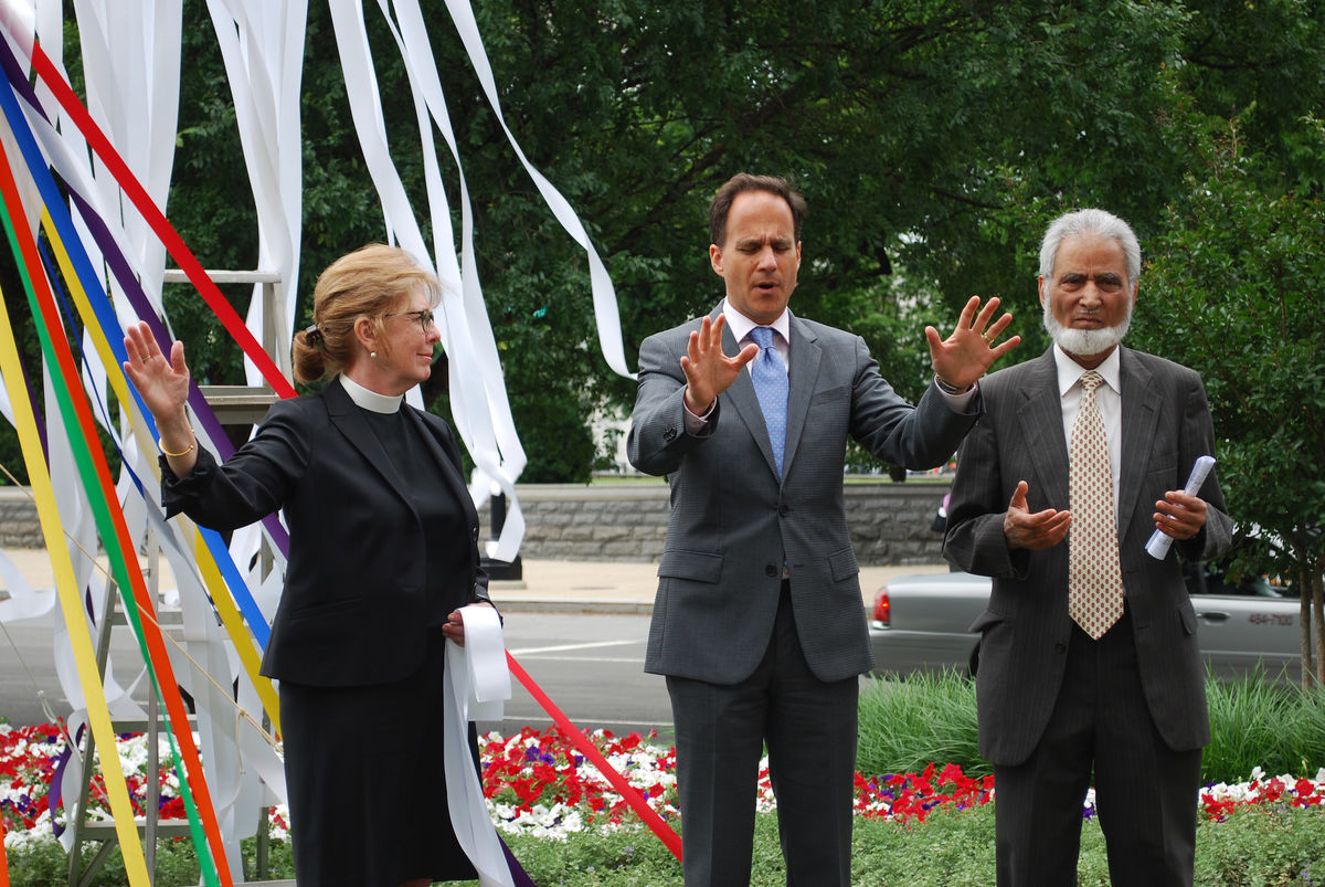 Three people lead prayer outside the United Methodist Building