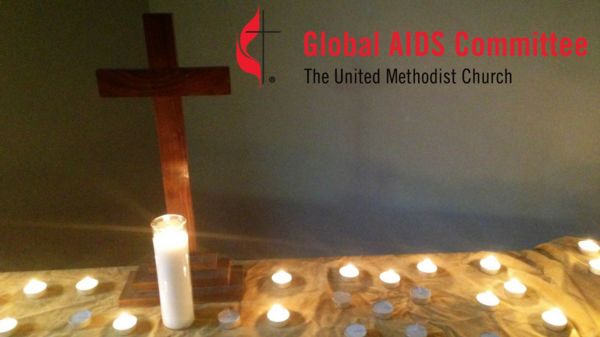 Cross on table surrounded by tea light candles with the United Methodist Global AIDS committee Logo (the UM Cross and Flame with the words "Global AIDS committee").
