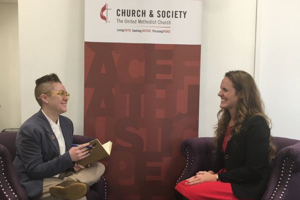 Quinn and Megan chat in two arm chairs at Church and Society's UN office. 