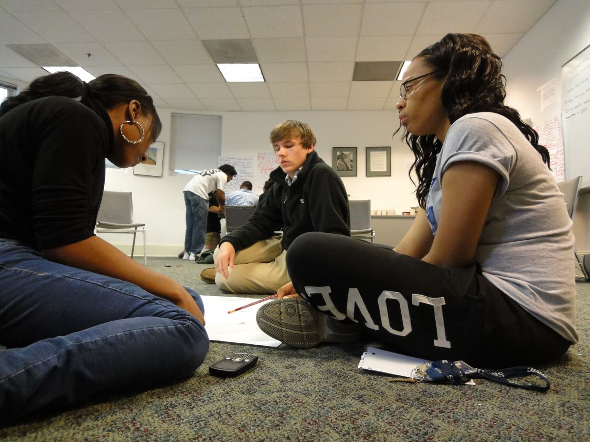 Three students sitting on the floor.