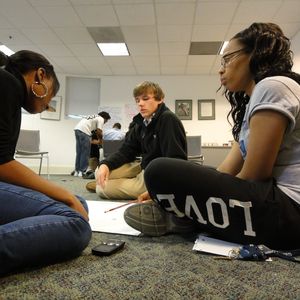 Three students sitting on the floor.
