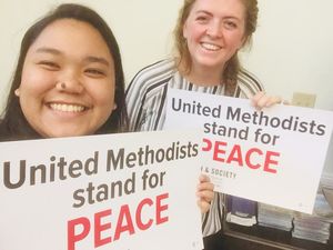 Church and Society fellows hold signs calling for peace ahead of a demonstration.