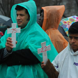 Two men hold crosses with numbers representing those killed in immigration raids