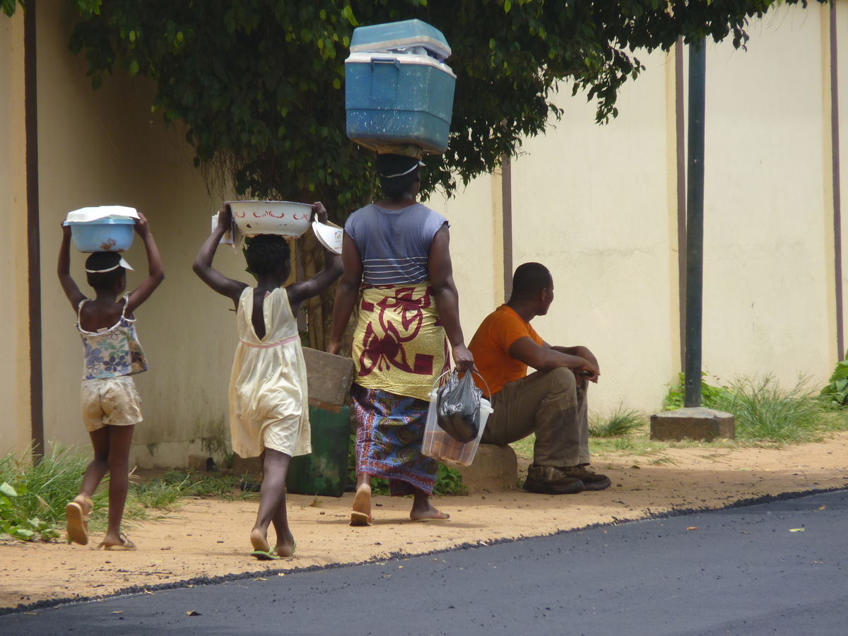 An adult and two children carry food on their heads