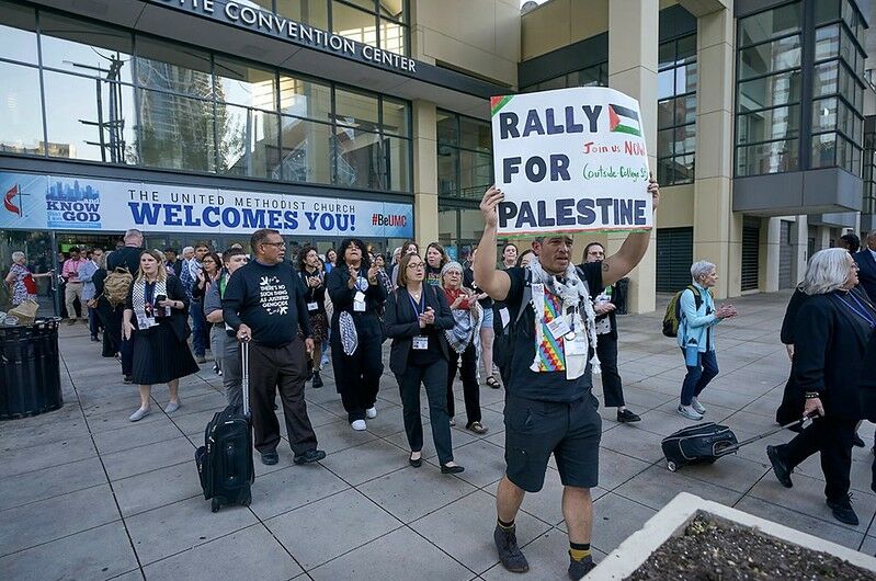A photo of protesters, one holding up a sign that says "Rally for Palestine"