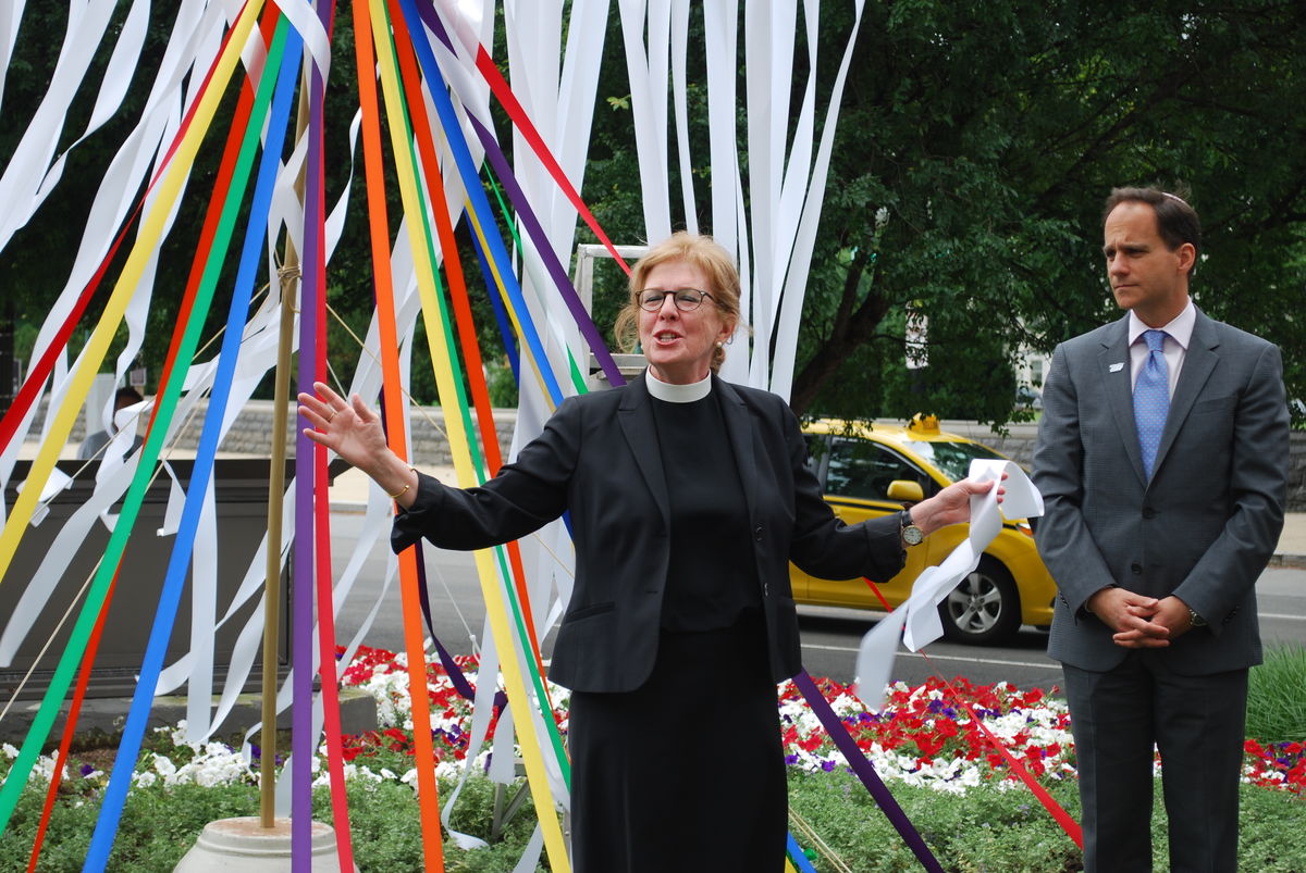 Church and Society General Secretary Leads Vigil following the Pulse Nightclub Massacre with rainbow ribbons behind her.