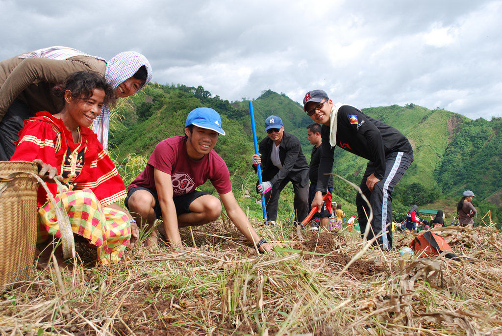 Group with seven people work through hay on a farm.