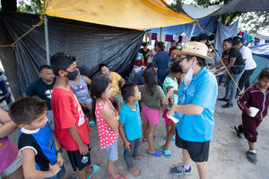 United Methodist Deaconess Cindy Johnson visits with children at a makeshift camp for migrants in the Plaza de la República in Reynosa, Mexico. About 2,000 migrants, many from Central America, have taken up residence in the plaza, just yards away from the McAllen - Hidalgo International Bridge into the U.S. Many of those living in the camp were deported from the U.S. under Title 42, a Centers for Disease Control and Prevention order that allows the U.S. to rapidly expel migrants for public health reasons during the COVID-19 pandemic. Photo by Mike DuBose, UM News.