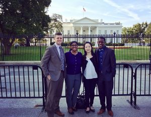 Four people stand in front of the White House.